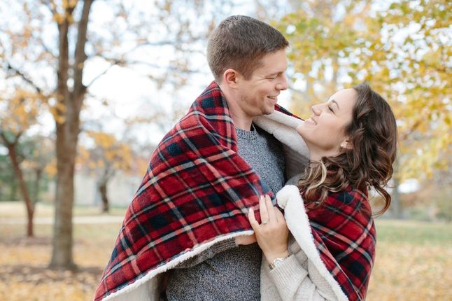 Couple posing in park wrapped in blanket
