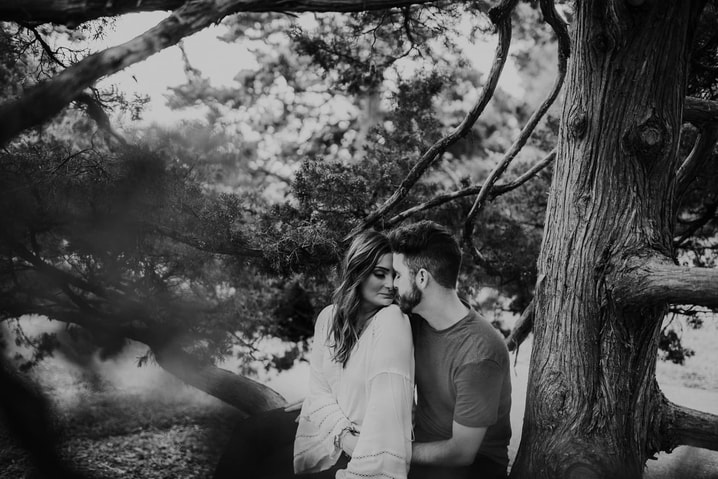 Black and white photo of couple posing next to tree