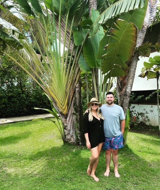 Couple posing in front of palm tree